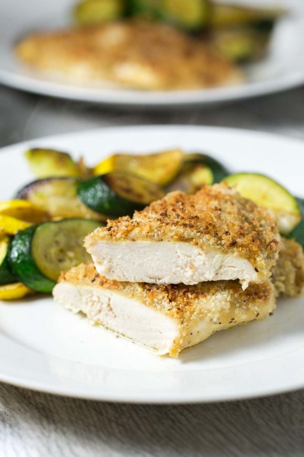 honey mustard chicken with crispy coating on a white plate with sauteed squash