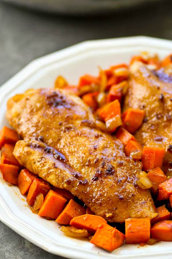 maple glazed skillet chicken breasts on white plate with chopped carrots on the plate
