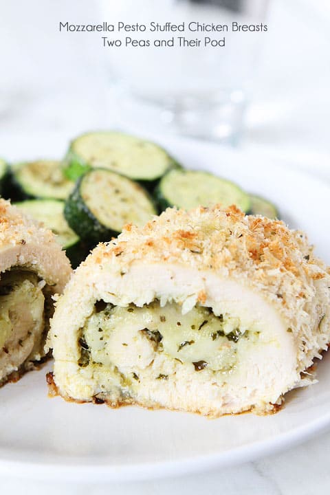 mozza pesto stuffed chicken breasts with crispy coating on a white plate with zucchini rounds