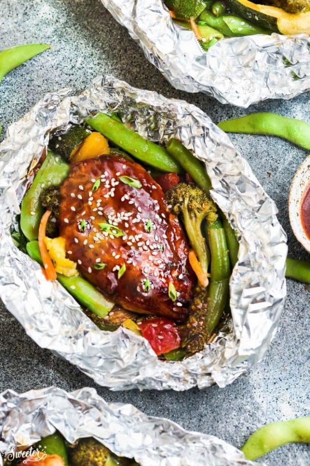 teriyaki chicken foil pack with lots of vegetables on grey background
