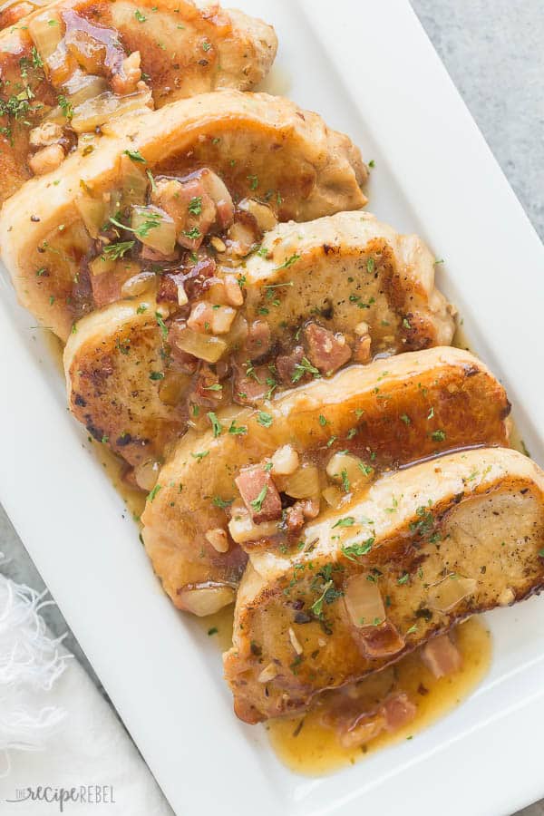 instant pot pork chops with glaze and bits of bacon and onions over top on white plate