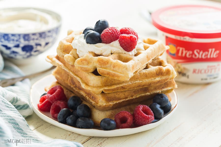 ricotta waffles on plate with berries and tre stelle ricotta cheese tub in the background