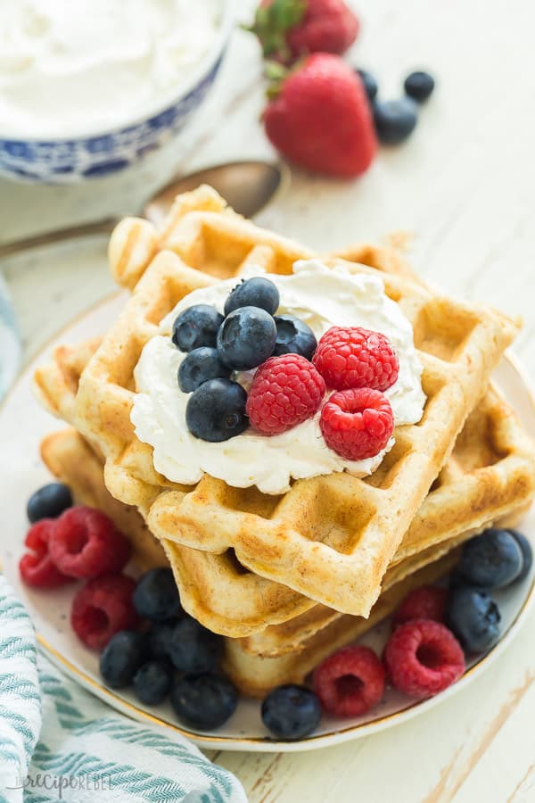 ricotta waffles with whipped cream and fresh berries in a stack on a plate