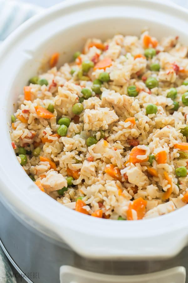 slow cooker chicken and rice in white crockpot with peas and carrots