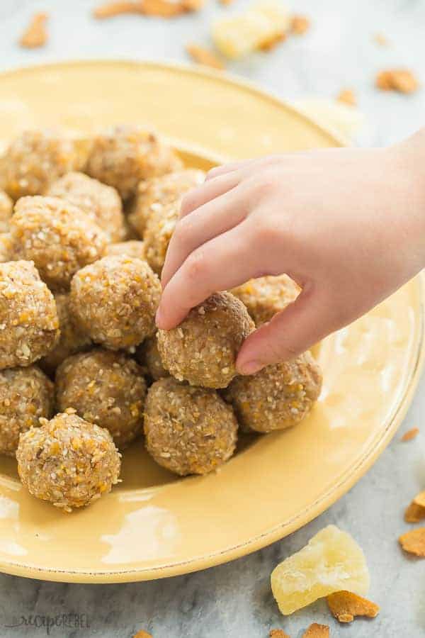 tropical energy bites on a yellow plate with child's hand reaching for one energy bite