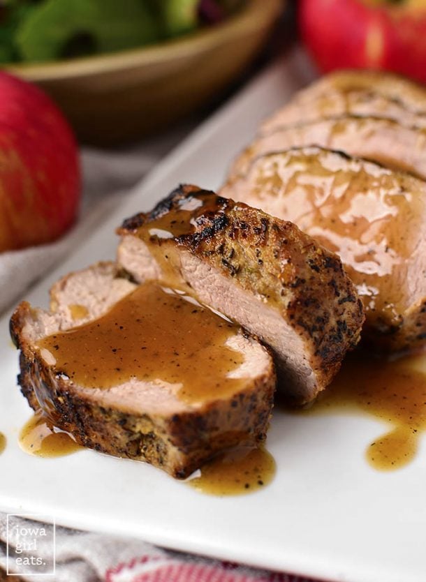 maple dijon cider pork tenderloin sliced with extra sauce and apples in the background