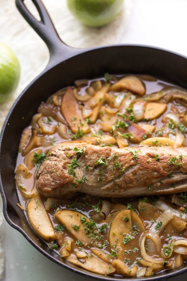 apple braised pork tenderloin recipe in cast iron skillet with a sprinkling of fresh parsley