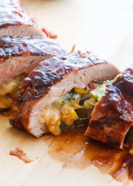 stuffed bbq pork tenderloin with vegetables and cheese inside sliced on cutting board