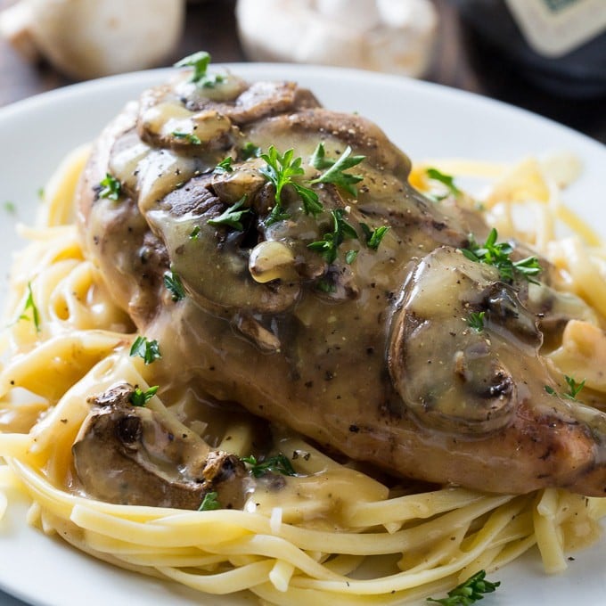 crockpot chicken marsala with mushrooms on a bed of linguine on a white plate