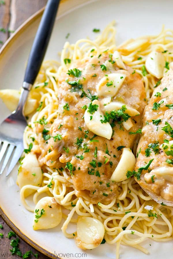 crockpot chicken 40 cloves of garlic closse up on plate with fresh parsley garnish