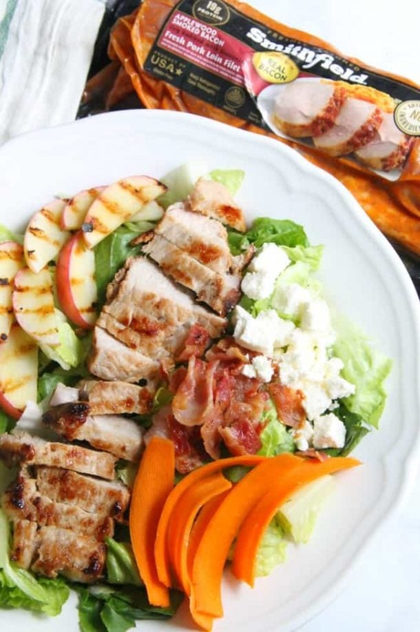 pork tenderloin salad with grilled apples bacon and carrots on white plate