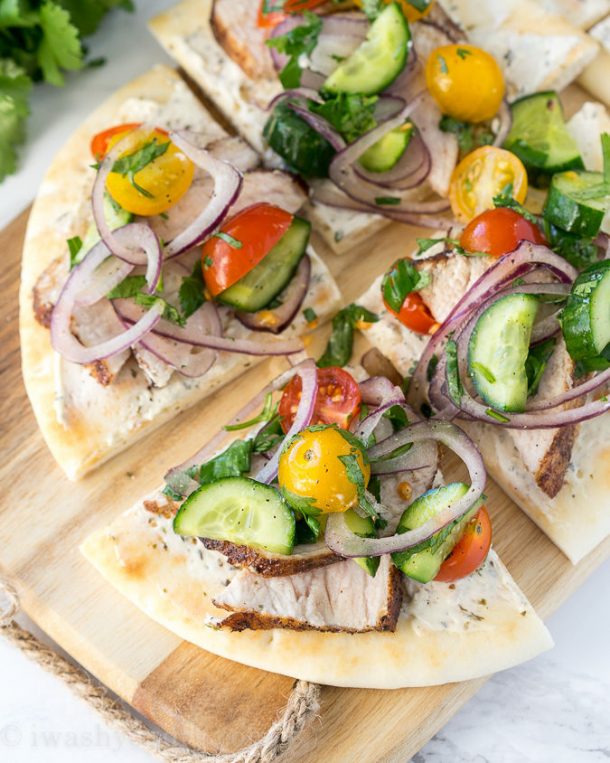 pork tenderloin flatbread recipe with onions tomatoes cucumbers on a wooden cutting board