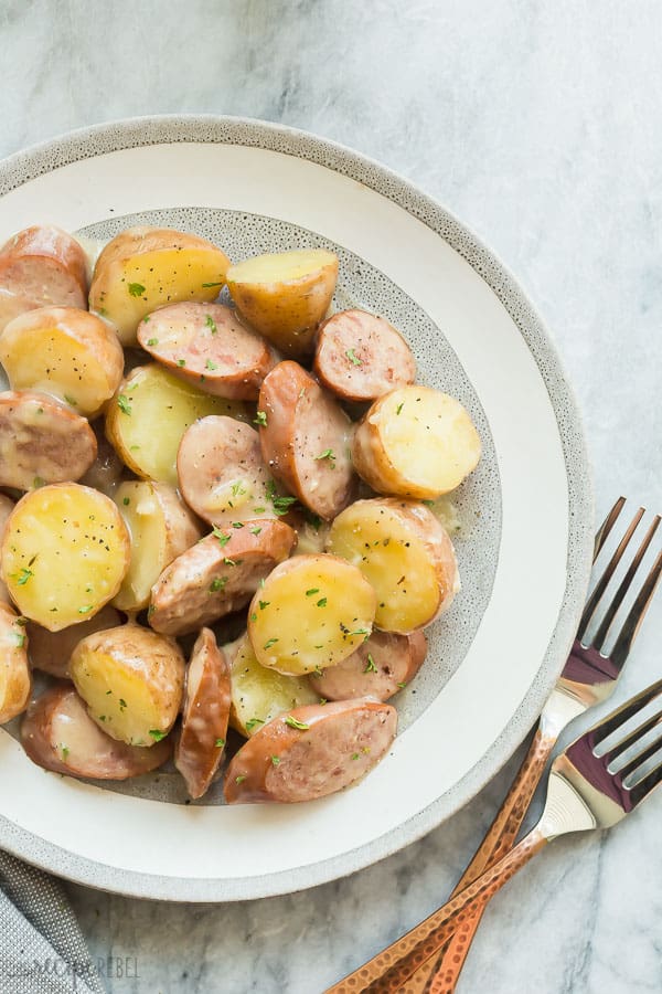 skillet sausage and potatoes in grey plate on grey marble background with two forks on the side