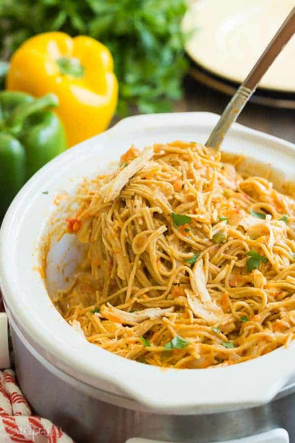 crockpot spaghetti with chicken with metal scoop pulling spaghetti out of slow cooker