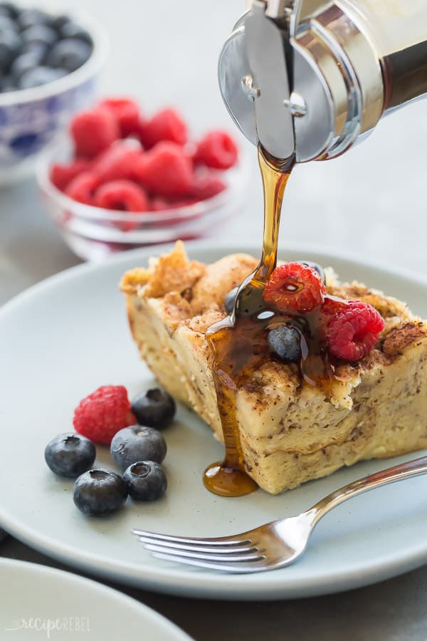 crockpot french toast with syrup drizzle and fresh raspberries and blueberries on the side