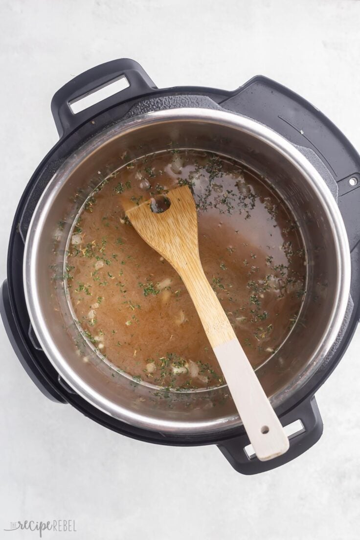 broth added to instant pot with wooden spoon.

