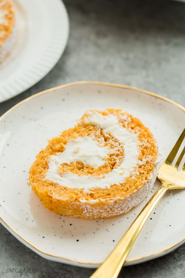 pumpkin roll single slice on white speckled plate with gold fork on the side