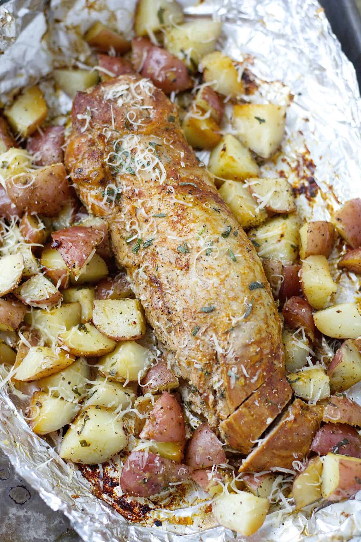 pork tenderloin and potato foil packages with shredded parmesan cheese on top