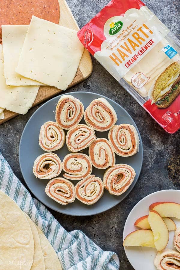 tortilla roll ups overhead on grey plate with arla havarti slices and package on the side