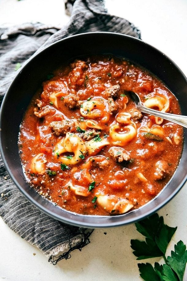 ground beef crock pot lasagna soup in black bowl with spoon stuck into soup