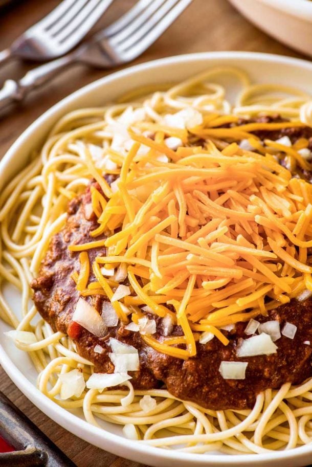 ground beef crock pot cincinnati chili over plain spaghetti with shredded cheddar cheese and raw diced onion