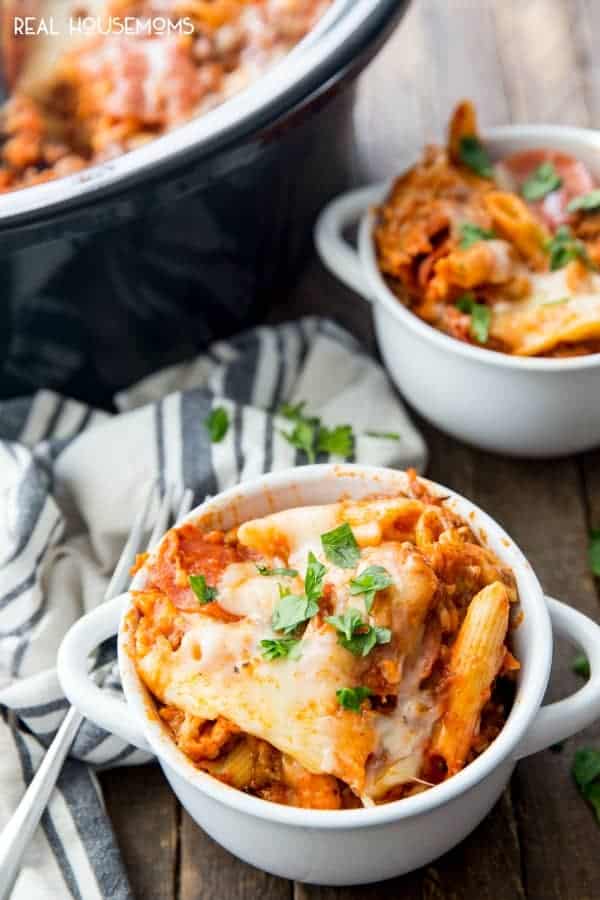 ground beef crock pot pizza casserole in two white bowls with striped towel in the background