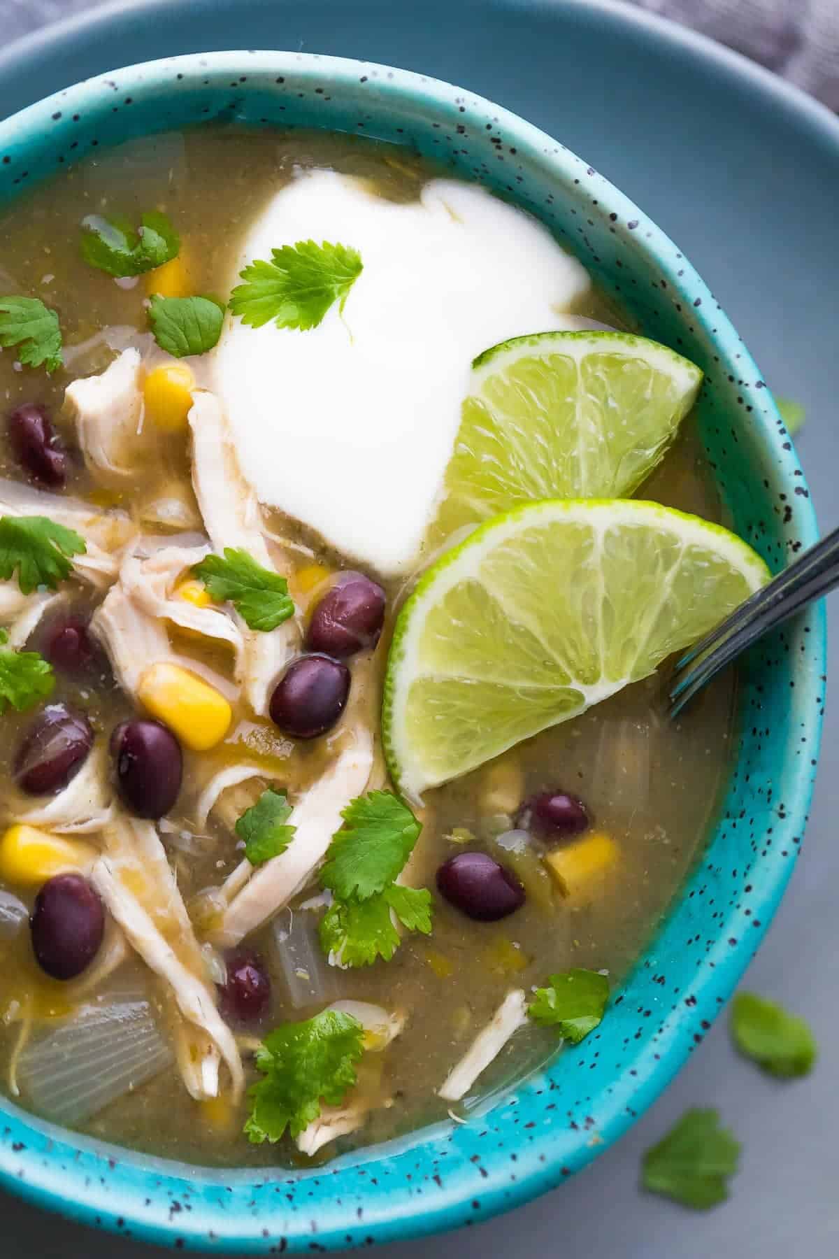 instant pot chicken chile verde soup close up in blue bowl with lime slices