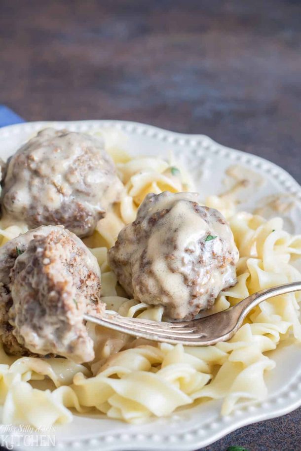 ground beef crock pot swedish meatballs close up on plain noodles on white plate