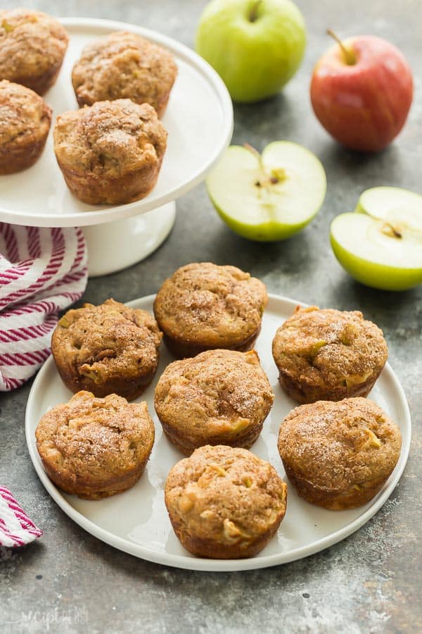 cinnamon apple muffins on a plate on grey background with halved apples in the background