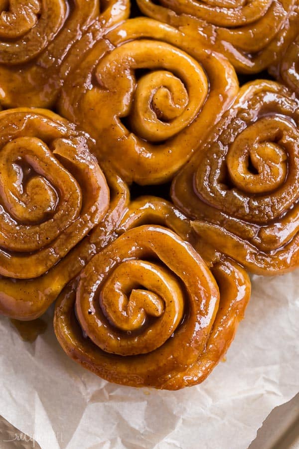 cinnamon buns overhead close up of gooey caramel on parchment paper