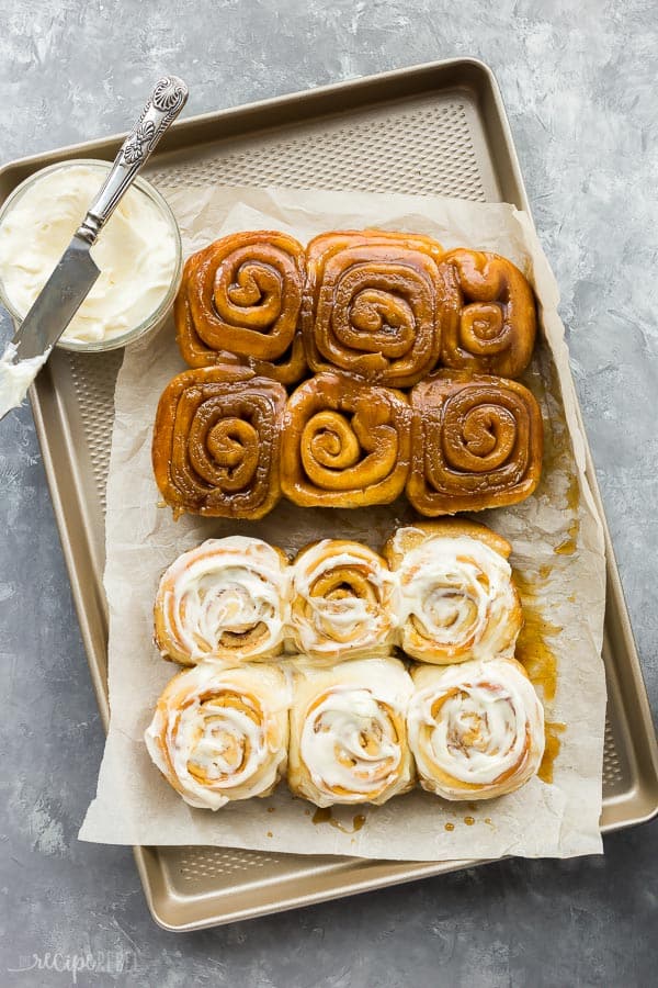 Des brioches à la cannelle sur une plaque à rebord sur un morceau de papier sulfurisé avec un caramel moitié givré et moitié gluant