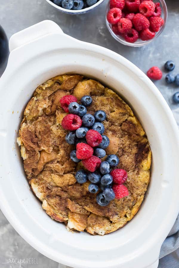 crockpot french toast overhead in slow cooker overhead with fresh blueberries and raspberries on top