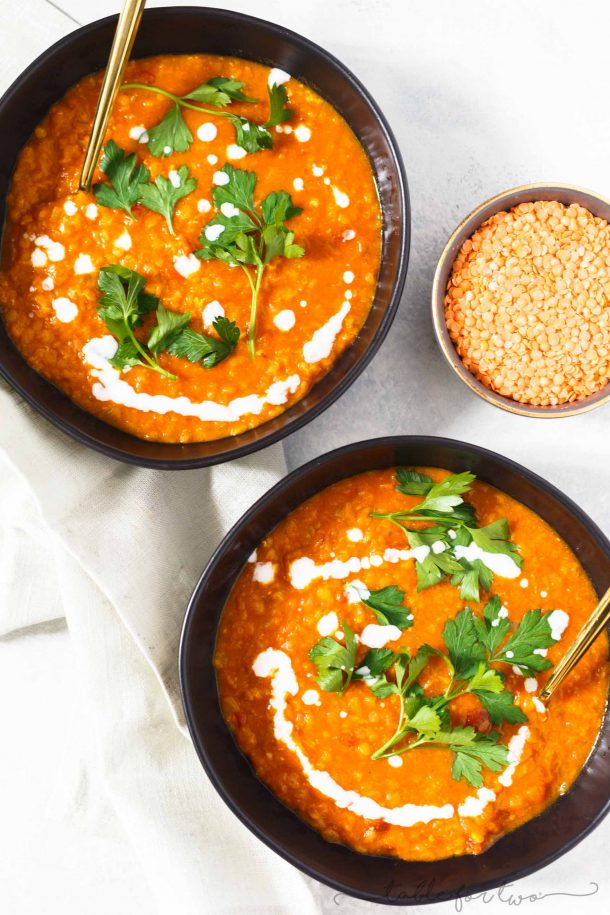 instant pot curried coconut lentil soup in two brown bowls with cilantro and cream on top