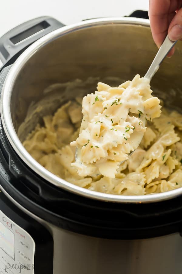 instant pot chicken alfredo pasta in pressure cooker with metal scoop scooping some out