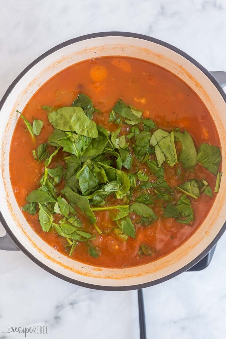 fresh spinach being added to minestrone soup