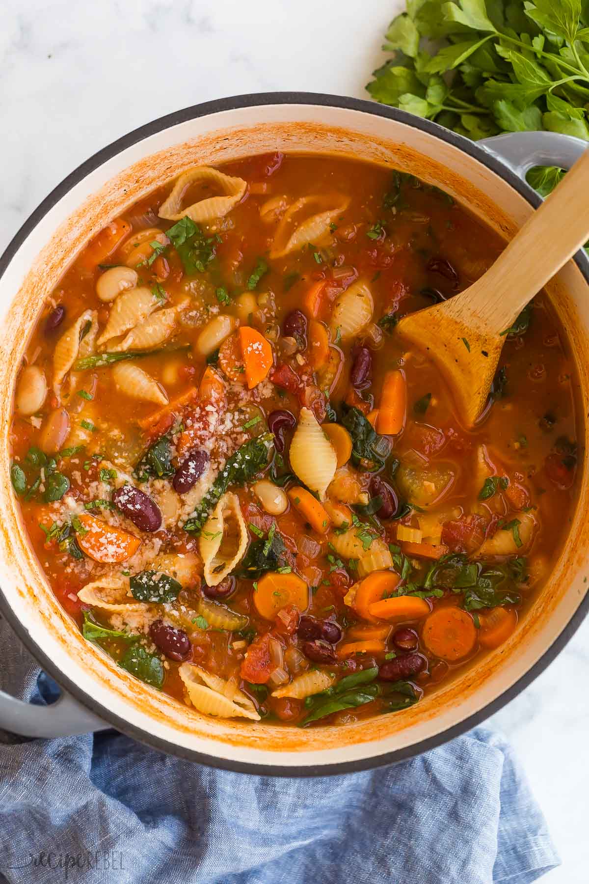 overhead image of pot of minestrone soup with wooden spoon stuck in