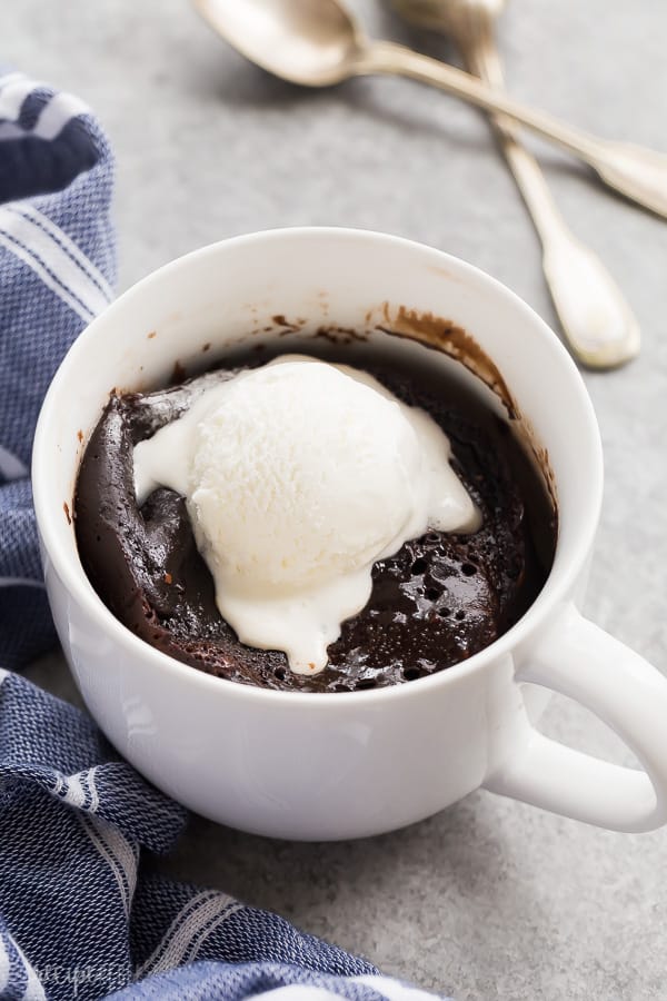 chocolate mug cake with ice cream melting on top and spoons in the background