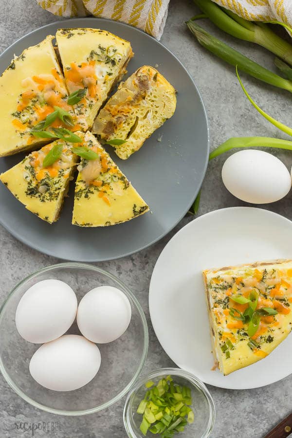 sausage egg casserole overhead on grey plate sliced and one slice on white plate with whole eggs and green onions on the side