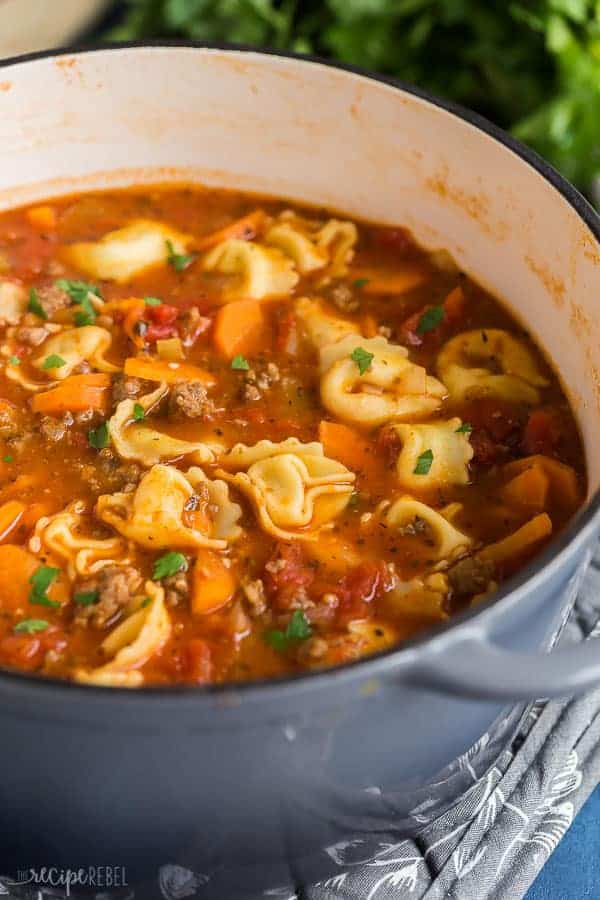 sausage tortellini soup in grey dutch oven with fresh parsley sprinkled on top