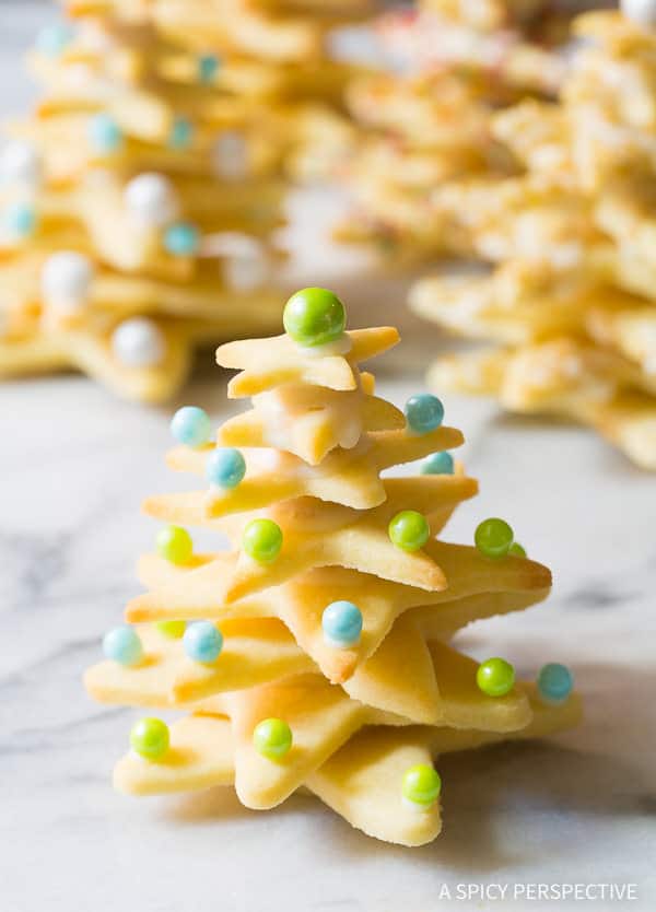3d christmas cookies made from sugar cookie stars and stacked then decorated with round sprinkles