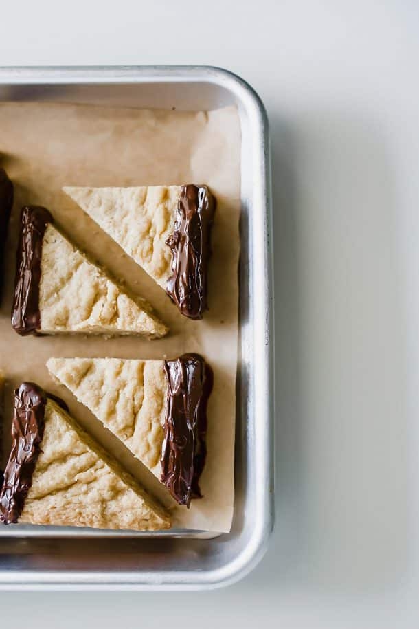 triangular chocolate dipped shortbread cookies on baking sheet with parchment paper
