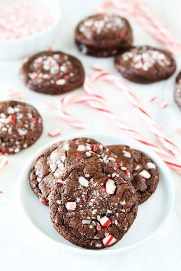 chocolate peppermint cookies with crushed candy canes and candy canes in the background