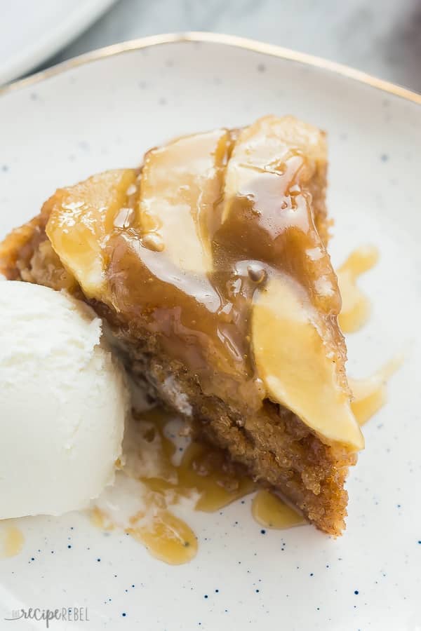 apple upside down cake with ice cream and caramel sauce on white speckled plate