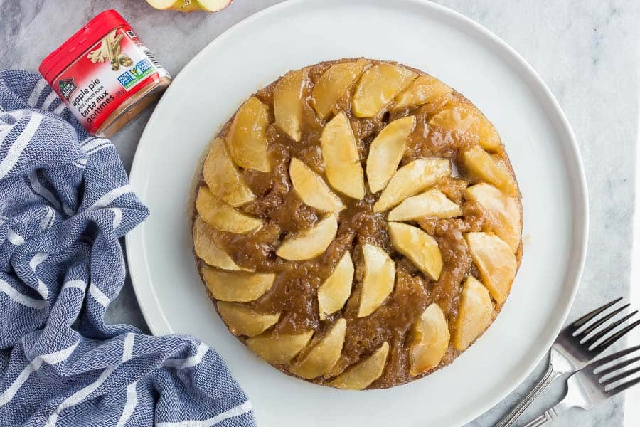 caramel apple upside down cake on white plate with blue striped towel on the side