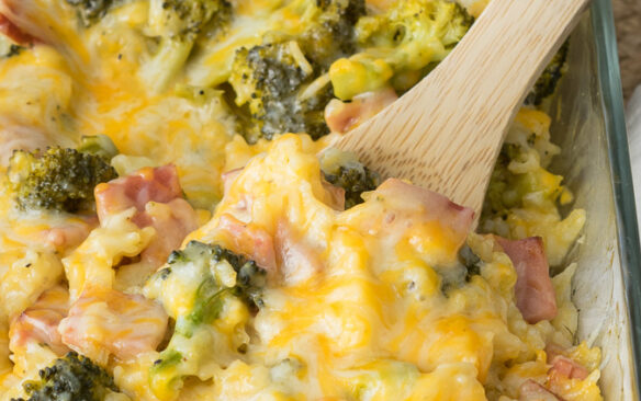 Ham and rice casserole is scooped up with a wooden spoon.