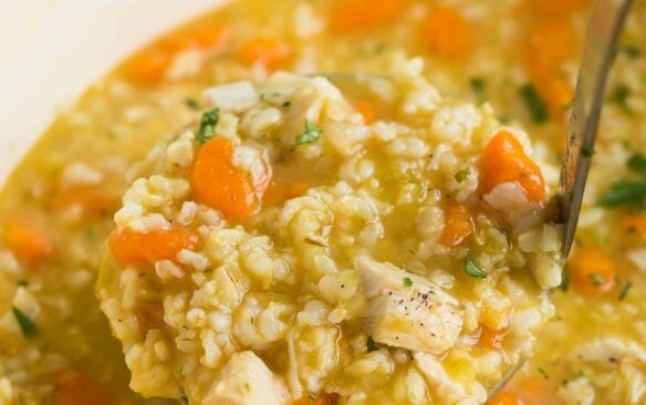 square image of chicken rice soup coming out of pot.