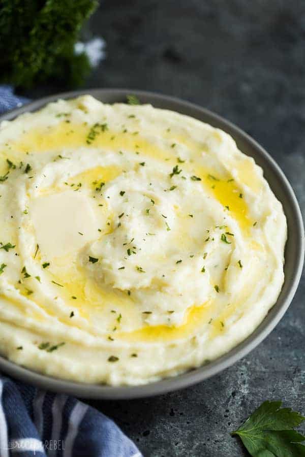 cream cheese mashed potatoes with butter close up in grey bowl on dark grey background