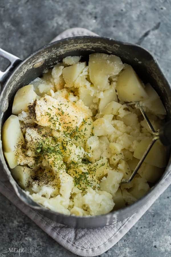 These easy Cream Cheese Mashed Potatoes are smooth, creamy and decadent! Perfectly seasoned with garlic and herbs -- once you make them this way you'll never go back! #potato #potatoes #recipe #dinner #recipes mashed potatoes with cream cheese in black pot ready for mashing