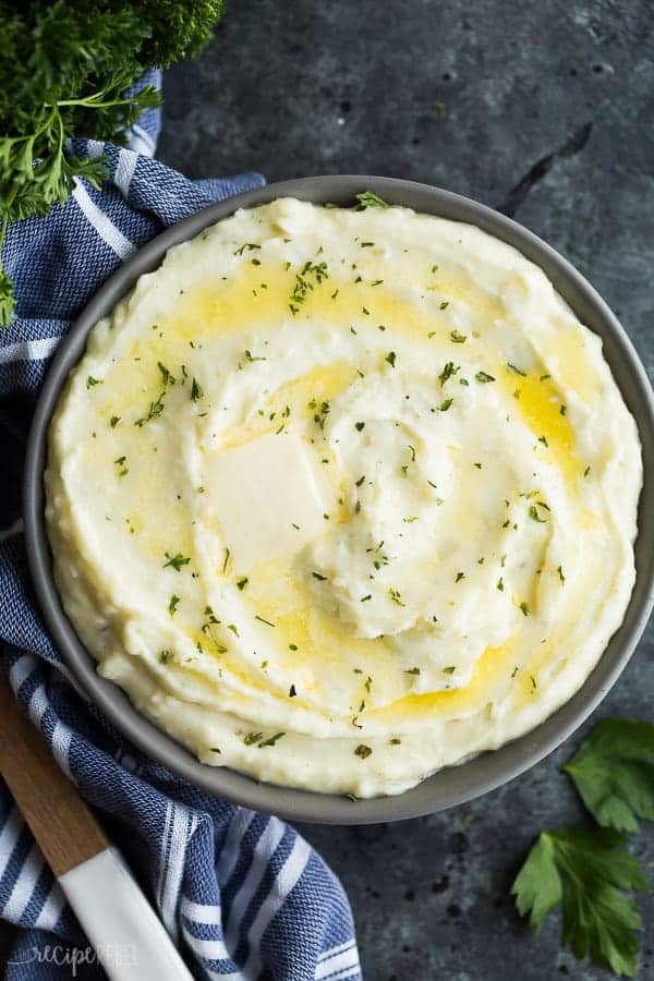 These easy Cream Cheese Mashed Potatoes are smooth, creamy and decadent! Perfectly seasoned with garlic and herbs -- once you make them this way you'll never go back! #potato #potatoes #recipe #dinner #recipes cream cheese mashed potatoes overhead in grey bowl on dark grey background