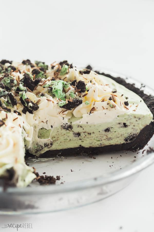 grasshopper pie in glass pie plate close up with whipped cream and crushed mint oreos on top